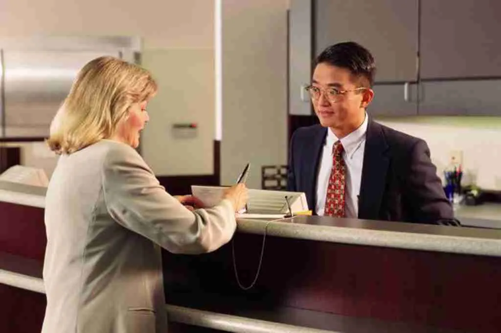 Male bank teller helping female customer over the counter